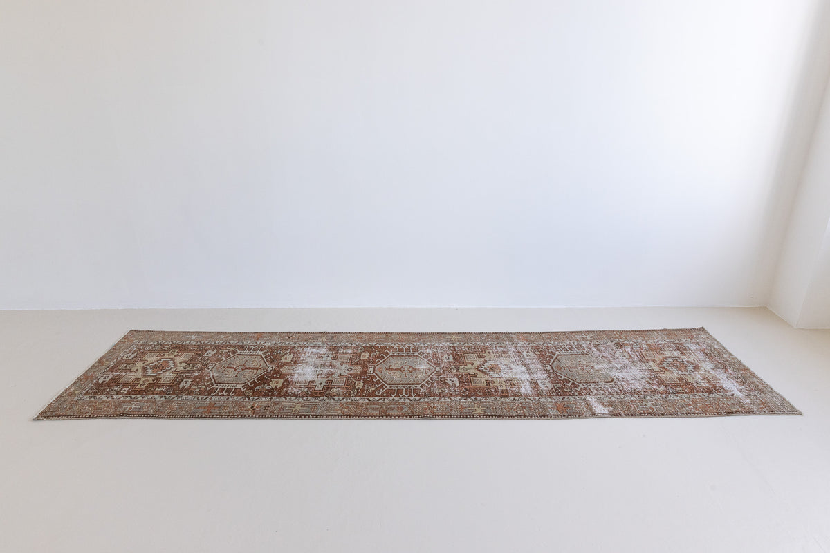 A vintage Persian Heriz runner in red and green tones — this hand-knotted antique carpet showcases a Karaja design.