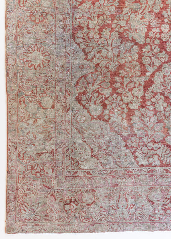 This is an antique Persian Sarouk rug, a handmade carpet in red and blue tones, featuring a floral medallion design.