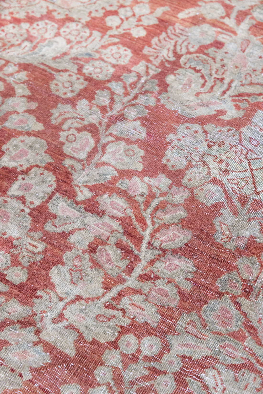 A vintage Persian Sarouk carpet in red and blue tones — this hand-knotted antique rug showcases a floral medallion design.