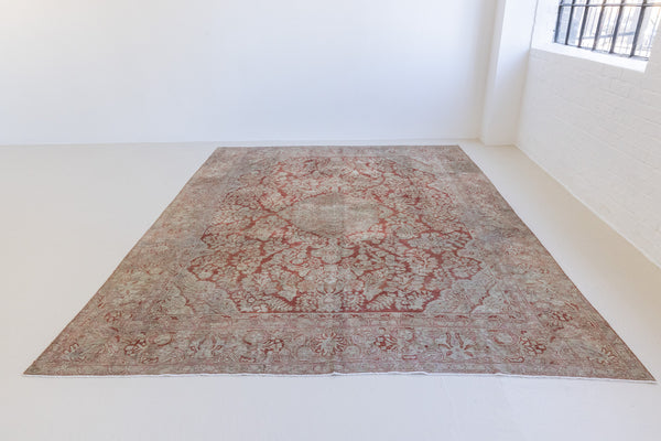 A vintage Persian Sarouk carpet in red and blue tones — this hand-knotted antique rug showcases a floral medallion design.
