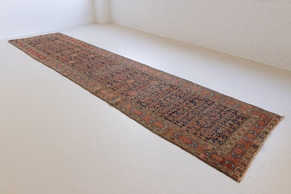 A vintage Persian Malayer runner in blue and red tones — this hand-knotted antique carpet showcases an all-over design.