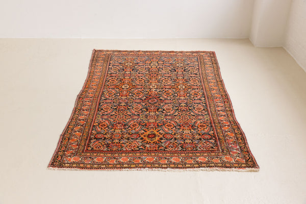 A vintage Persian Malayer carpet in red tones — this hand-knotted antique rug showcases a repeating pattern design.