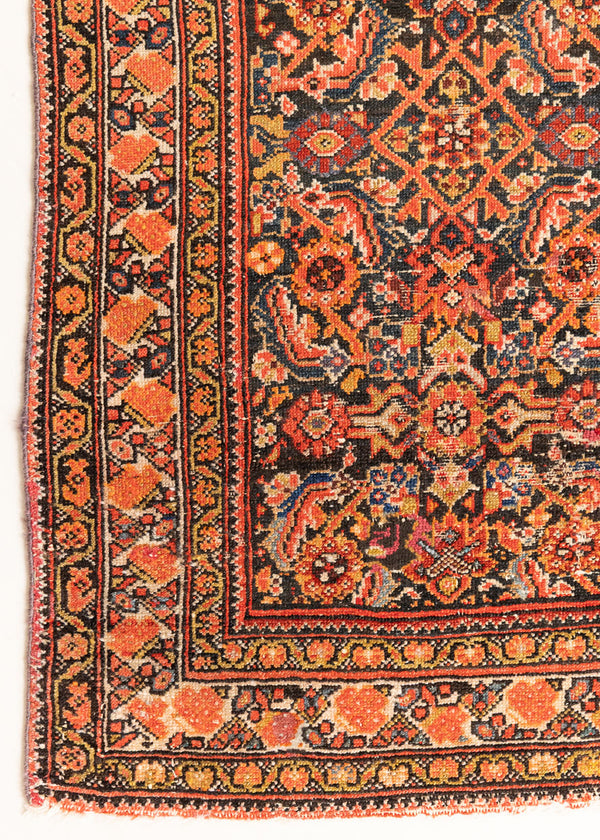 This is an antique Persian Malayer rug, a handmade carpet in red tones, featuring a repeating pattern design.