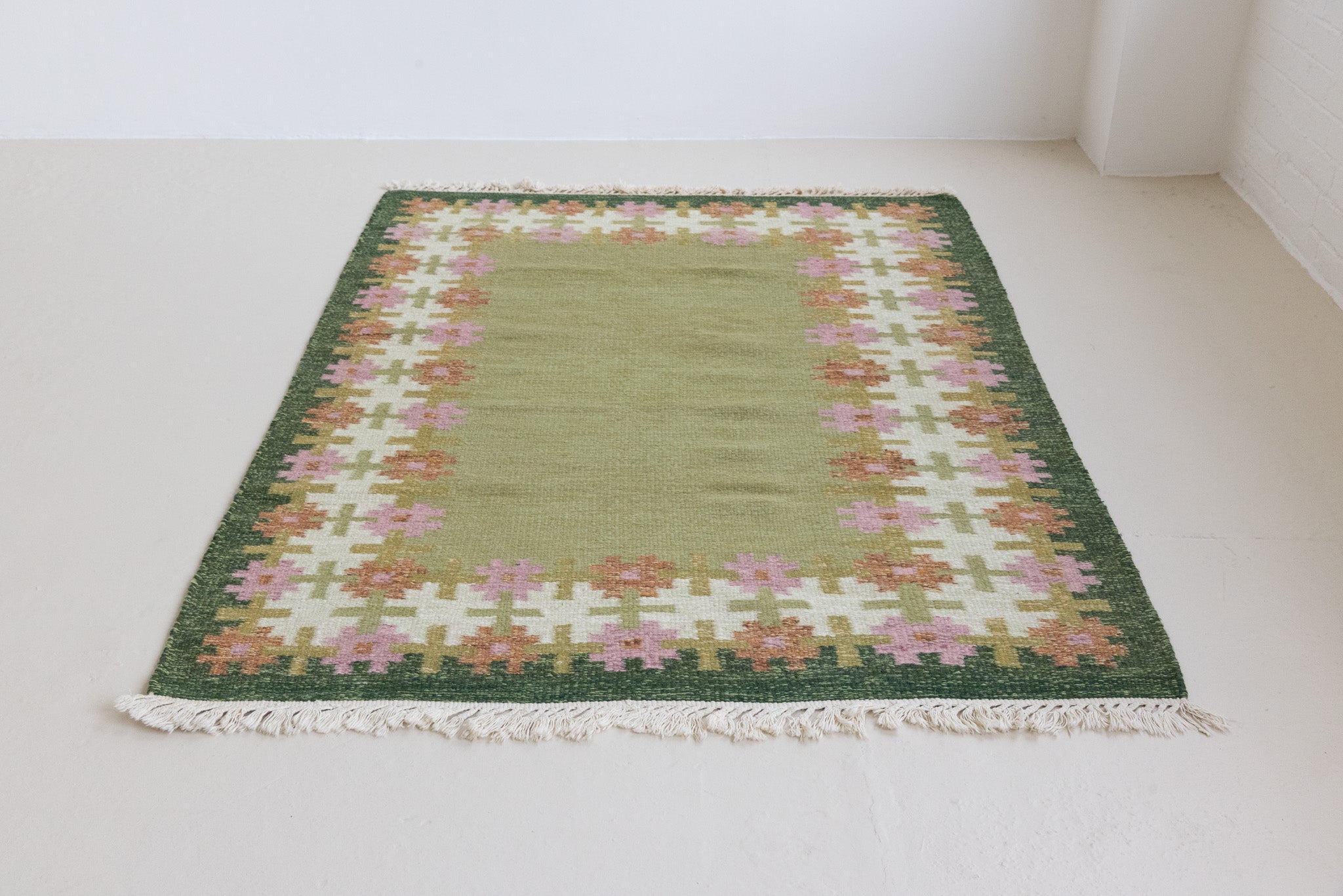 Handwoven vintage Swedish rug in green with a pretty geometric border in pink and rust