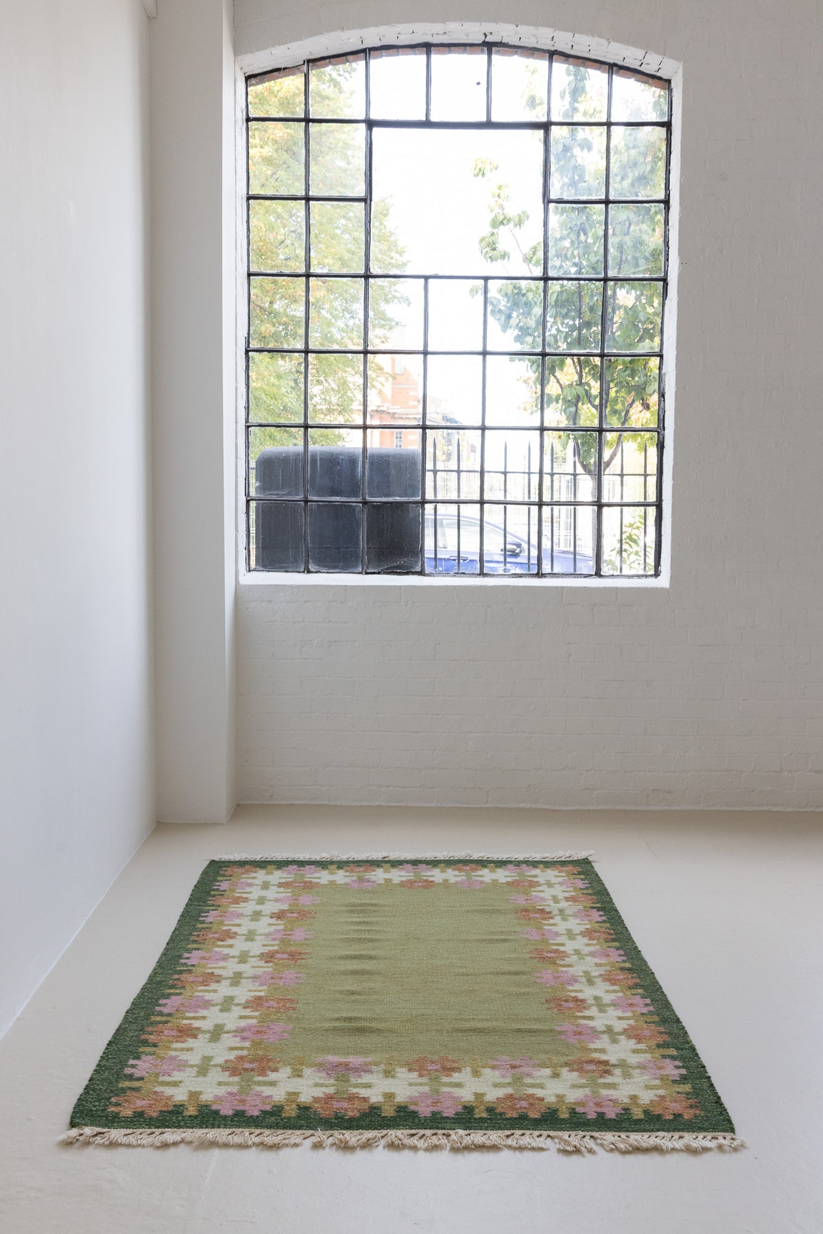 Handwoven vintage Swedish rug in green with a pretty geometric border in pink and rust