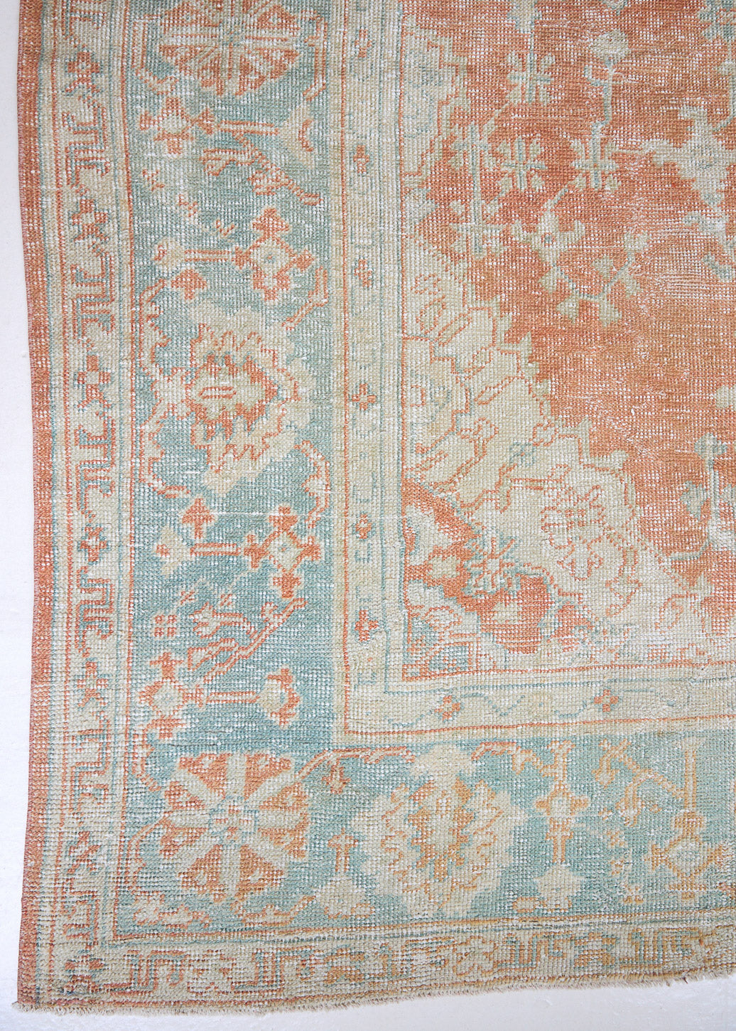 An antique Turkish Oushak rug. Perdita features a large-scale, open medallion pattern, flowing botanical motifs and a generous field space set against a blue and terracotta ground.