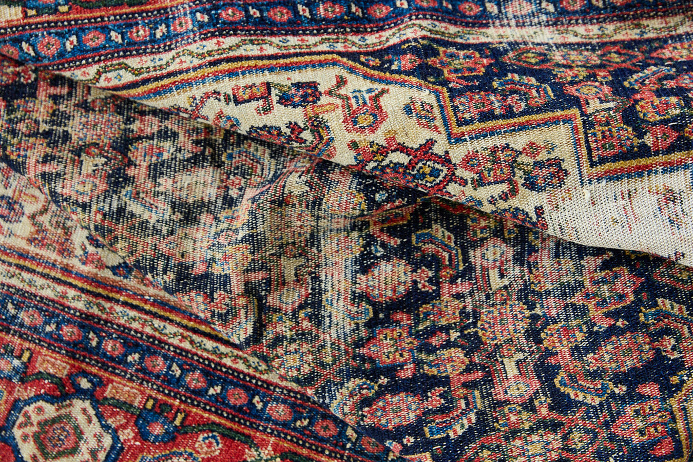 Raine is a beautiful antique Senneh rug with an intricate design. Senneh rugs are known for their fine and intricate patterns and distinctive weaving technique. Raine has a central motif surrounded by an intricate pattern and a pleasing colour palette of blue, red and taupe.