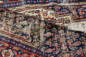 Raine is a beautiful antique Senneh rug with an intricate design. Senneh rugs are known for their fine and intricate patterns and distinctive weaving technique. Raine has a central motif surrounded by an intricate pattern and a pleasing colour palette of blue, red and taupe.