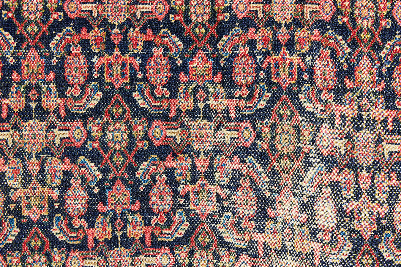 Raine is a beautiful antique Senneh rug with an intricate design. Senneh rugs are known for their fine and intricate patterns and distinctive weaving technique. Raine has a central motif surrounded by an intricate pattern and a pleasing colour palette of blue, red and taupe.