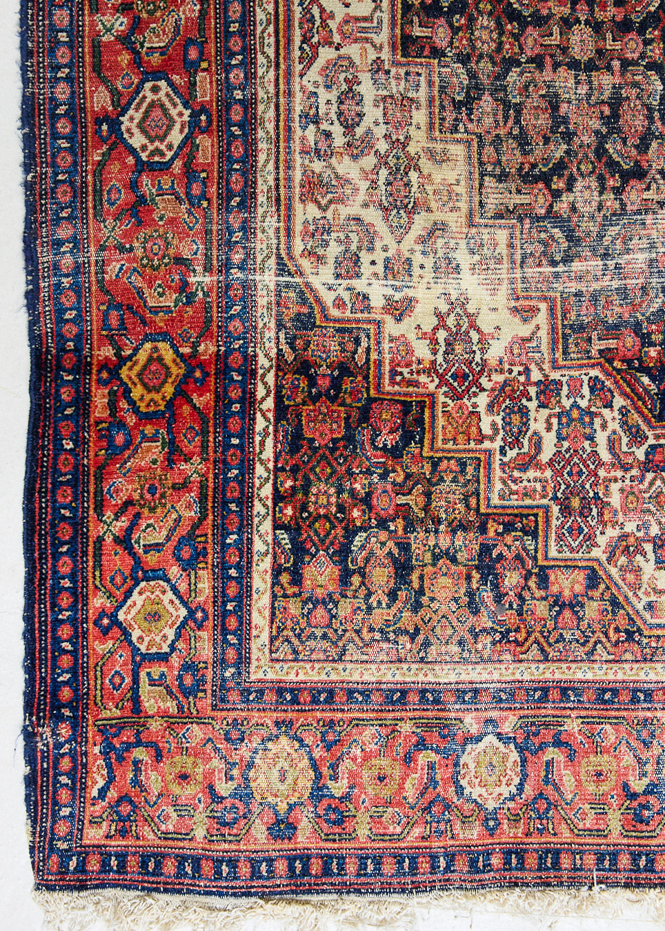 Raine is a beautiful antique Senneh rug with an intricate design. Senneh rugs are known for their fine and intricate patterns and distinctive weaving technique. Raine has a central motif surrounded by an intricate pattern and a pleasing colour palette of blue, red and taupe.
