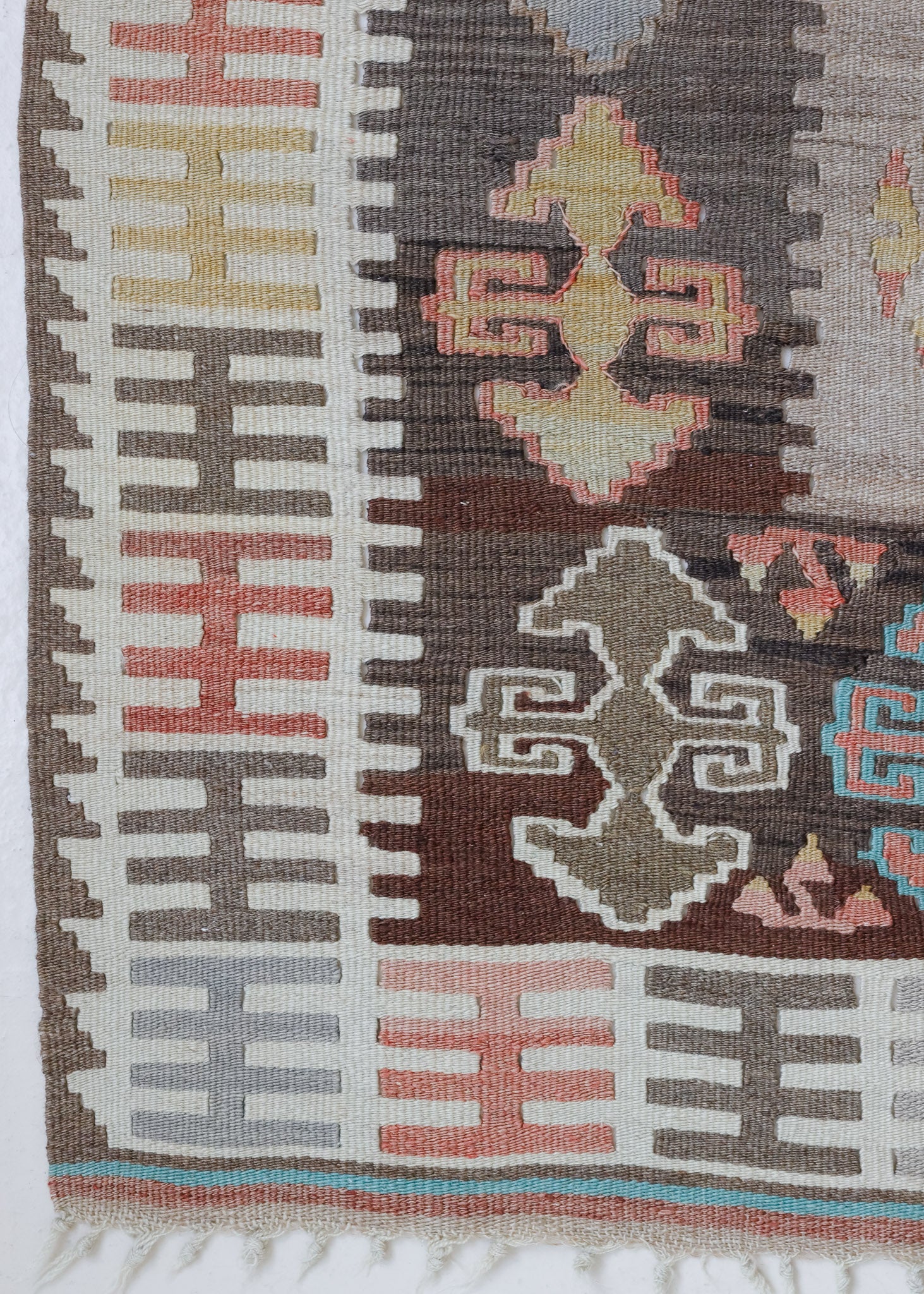 Close-up of a vintage Anatolian kilim rug with muted geometric designs on a white background