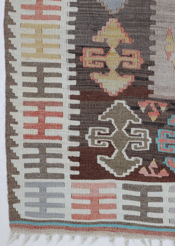 Close-up of a vintage Anatolian kilim rug with muted geometric designs on a white background