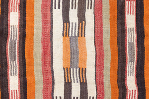 A South Anatolian nomadic kilim runner. Hand-woven on village and nomadic looms in vivid, naturally dyed colours, a tradition stretching back thousands of years. Vespa features a bold stripe pattern in earthy hues of rust, orange, taupe and black.