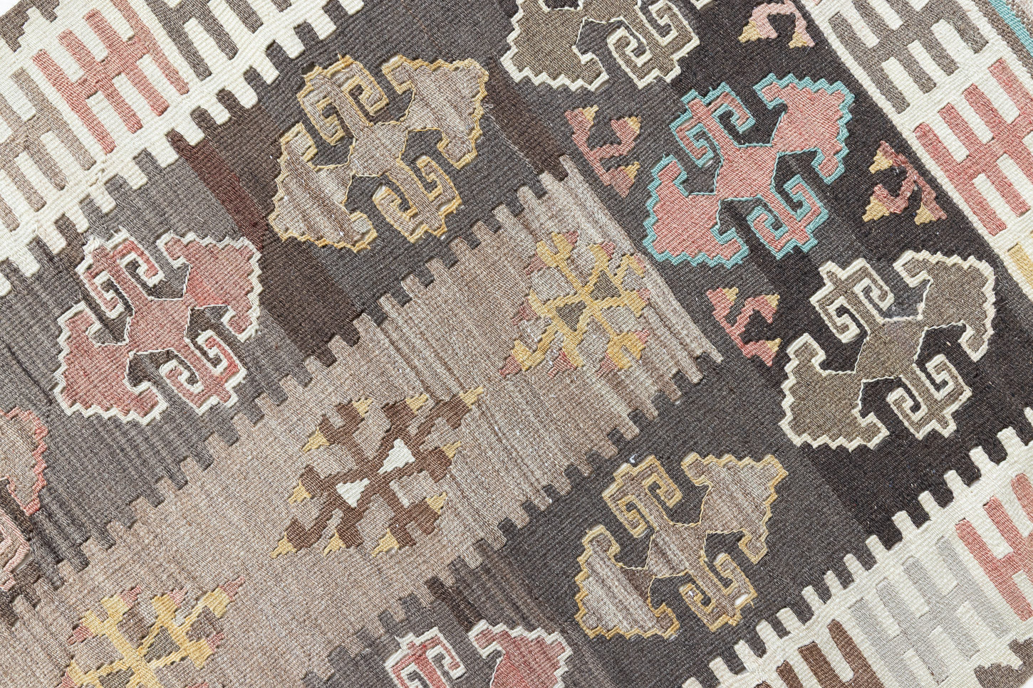 Close-up of an antique Anatolian kilim rug with geometric designs in brown, beige, and blue, featuring the traditional hand on hips motif