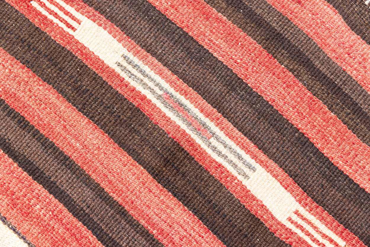 A South Anatolian nomadic kilim runner. Hand-woven on village and nomadic looms in vivid, naturally dyed colours, a tradition stretching back thousands of years. Vespa features a bold stripe pattern in earthy hues of rust, orange, taupe and black.