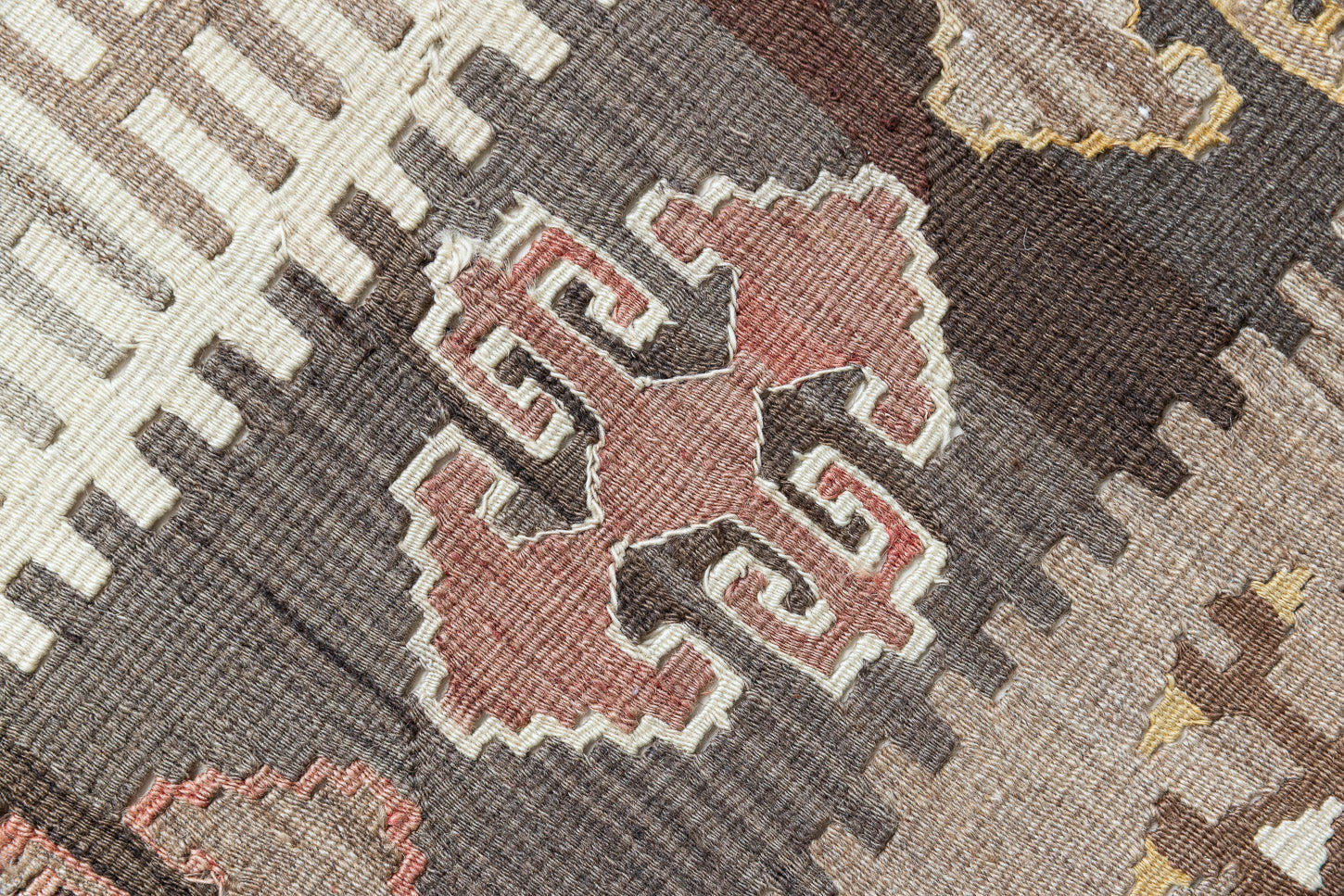 Close-up of an antique Anatolian kilim rug with geometric designs in brown, beige, and blue, featuring the traditional hand on hips motif