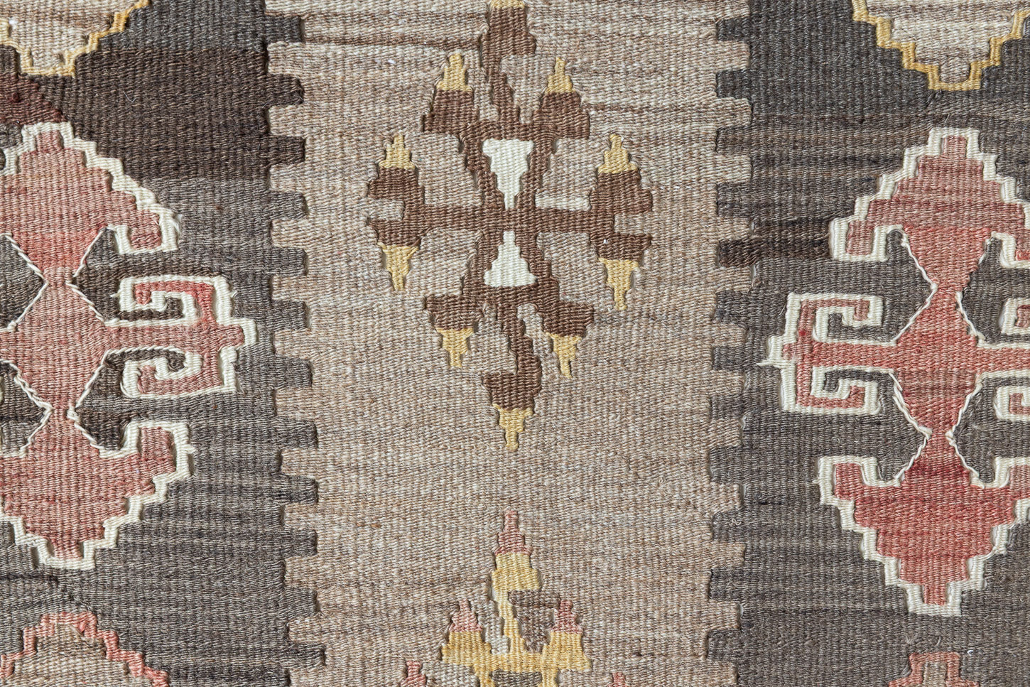 Close-up of an antique Anatolian kilim rug with geometric designs in brown, beige, and blue, featuring the traditional hand on hips motif
