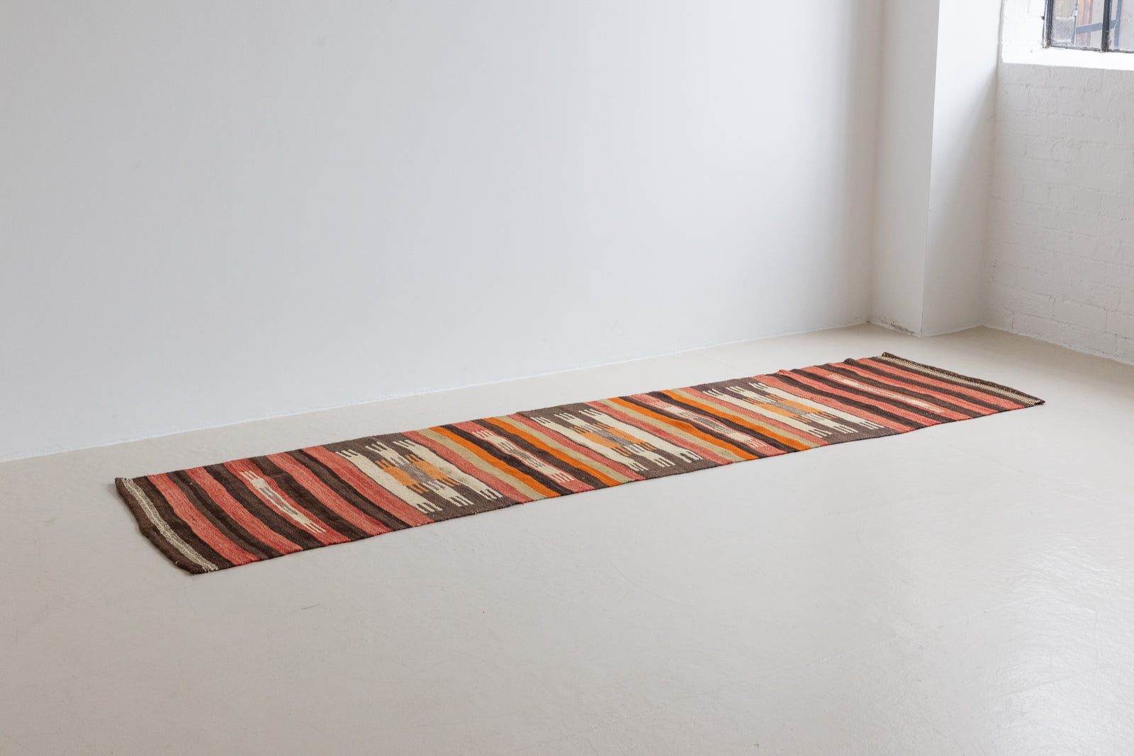 A South Anatolian nomadic kilim runner. Hand-woven on village and nomadic looms in vivid, naturally dyed colours, a tradition stretching back thousands of years. Vespa features a bold stripe pattern in earthy hues of rust, orange, taupe and black.