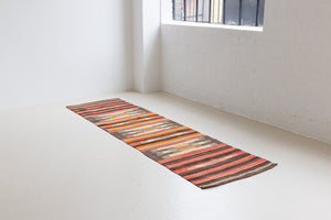 A South Anatolian nomadic kilim runner. Hand-woven on village and nomadic looms in vivid, naturally dyed colours, a tradition stretching back thousands of years. Vespa features a bold stripe pattern in earthy hues of rust, orange, taupe and black.