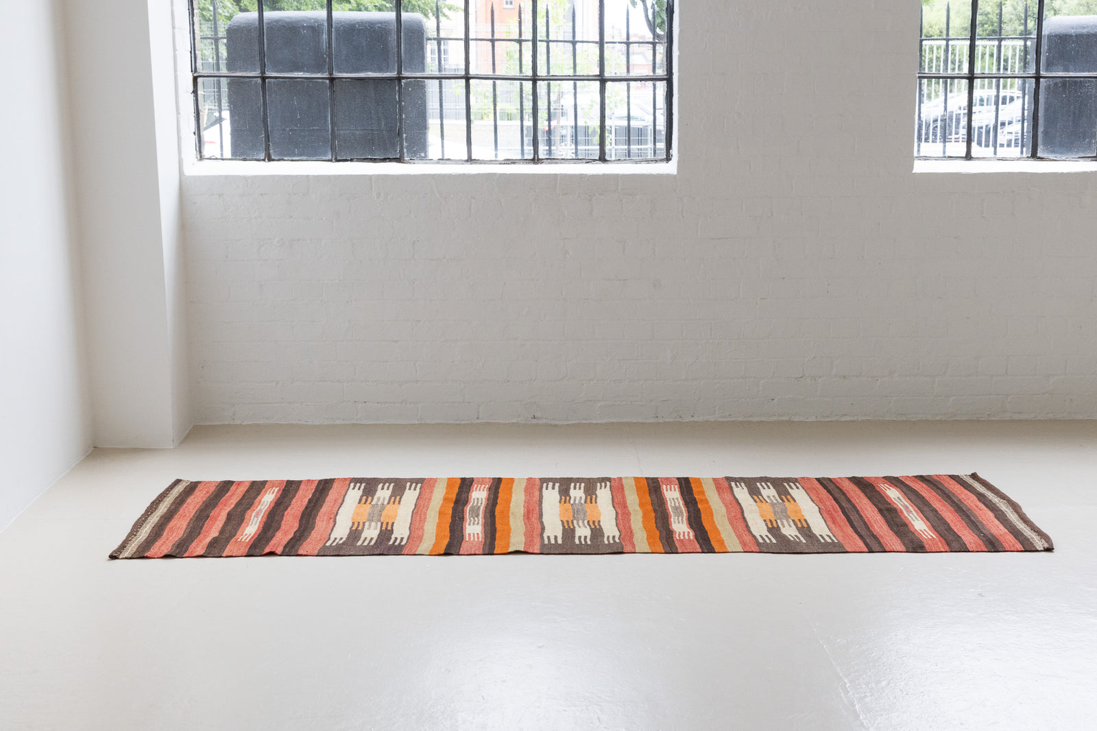 A South Anatolian nomadic kilim runner. Hand-woven on village and nomadic looms in vivid, naturally dyed colours, a tradition stretching back thousands of years. Vespa features a bold stripe pattern in earthy hues of rust, orange, taupe and black.