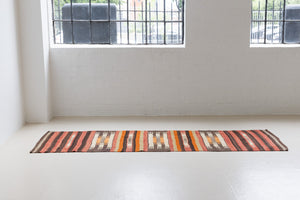 A South Anatolian nomadic kilim runner. Hand-woven on village and nomadic looms in vivid, naturally dyed colours, a tradition stretching back thousands of years. Vespa features a bold stripe pattern in earthy hues of rust, orange, taupe and black.