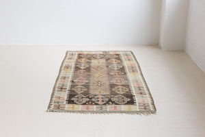 Close-up of a vintage Anatolian kilim rug with muted geometric designs on a white background