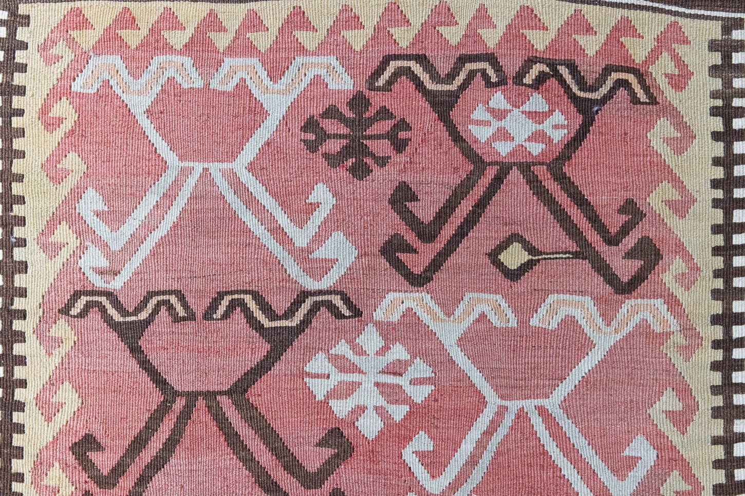 Delphi is a bold, geometric Anatolian kilim. Hand-woven on village and nomadic looms in vivid, naturally dyed colours, a tradition stretching back thousands of years. Kilims were woven for the practicalities of daily life and used as floor and wall coverings, storage bags, and prayer mats. Delphi features a rosey pink field scattered with a geometric motif. A black border is decorated with the Anatolian star motif traditionally associated with happiness.