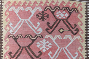 Delphi is a bold, geometric Anatolian kilim. Hand-woven on village and nomadic looms in vivid, naturally dyed colours, a tradition stretching back thousands of years. Kilims were woven for the practicalities of daily life and used as floor and wall coverings, storage bags, and prayer mats. Delphi features a rosey pink field scattered with a geometric motif. A black border is decorated with the Anatolian star motif traditionally associated with happiness.