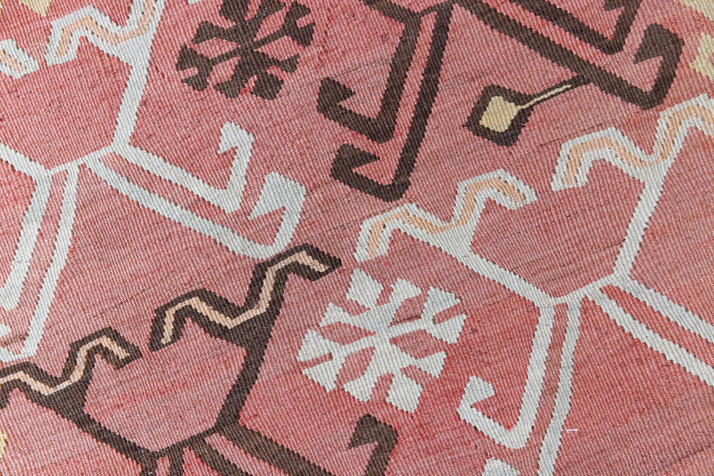 Delphi is a bold, geometric Anatolian kilim. Hand-woven on village and nomadic looms in vivid, naturally dyed colours, a tradition stretching back thousands of years. Kilims were woven for the practicalities of daily life and used as floor and wall coverings, storage bags, and prayer mats. Delphi features a rosey pink field scattered with a geometric motif. A black border is decorated with the Anatolian star motif traditionally associated with happiness.