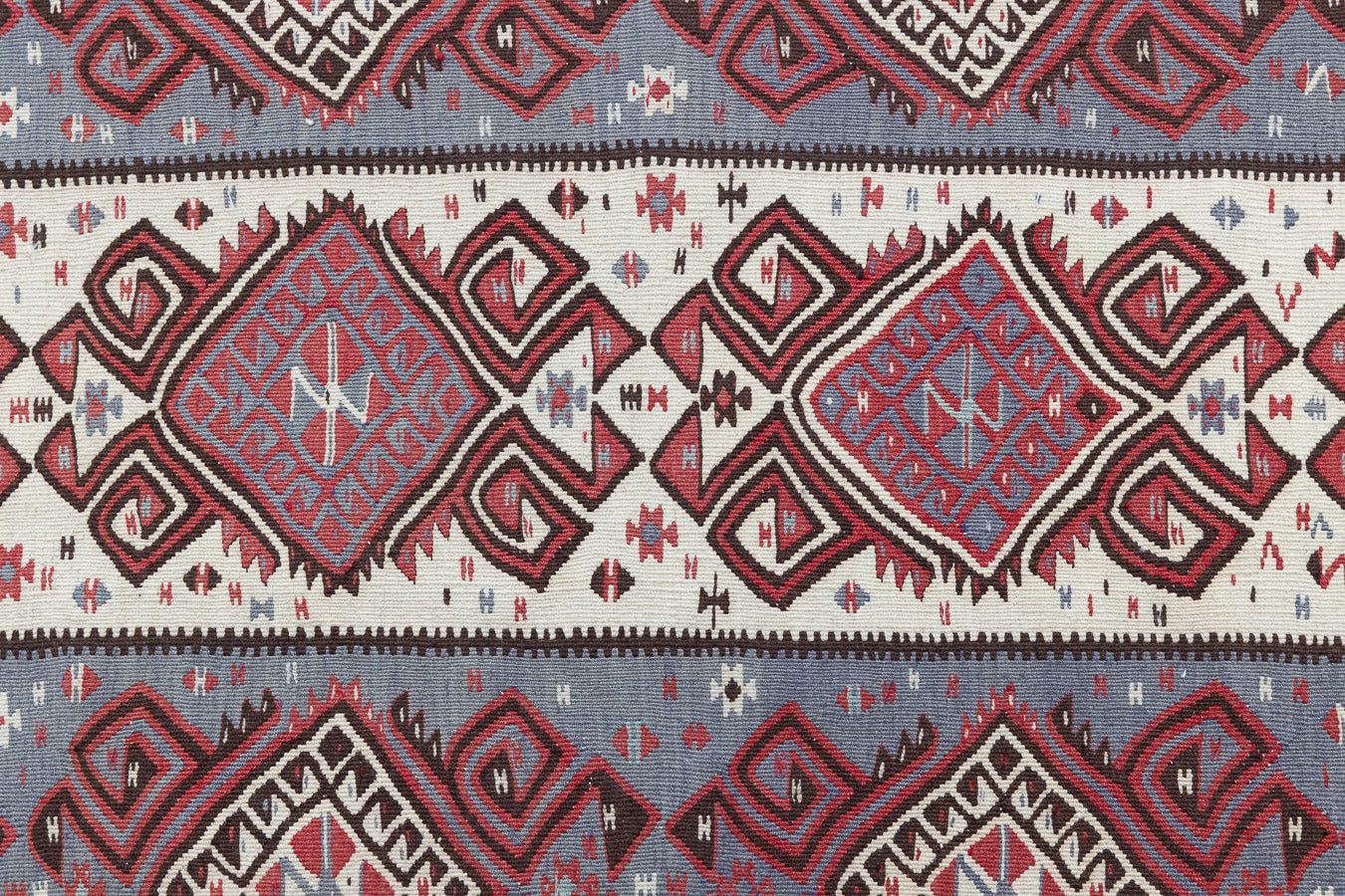 Zerrin is a bold, geometric Anatolian Hakkari kilim rug. This antique carpet features a taupe and grey striped field scattered with the classic hand-on-hips motif, bordered by the comb motif both traditionally associated with marriage and fertility.
