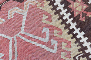 Delphi is a bold, geometric Anatolian kilim. Hand-woven on village and nomadic looms in vivid, naturally dyed colours, a tradition stretching back thousands of years. Kilims were woven for the practicalities of daily life and used as floor and wall coverings, storage bags, and prayer mats. Delphi features a rosey pink field scattered with a geometric motif. A black border is decorated with the Anatolian star motif traditionally associated with happiness.