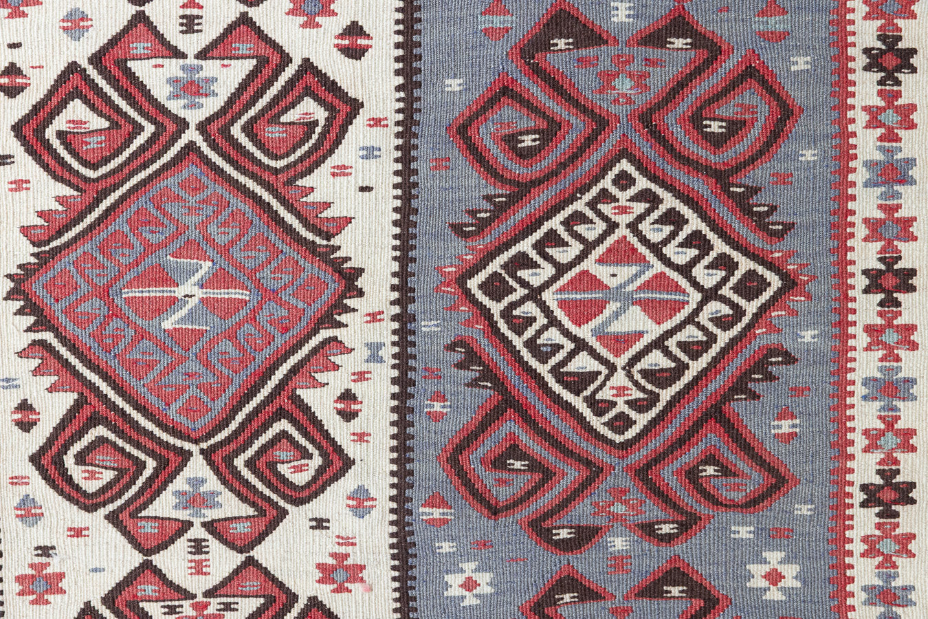 Zerrin is a bold, geometric Anatolian Hakkari kilim rug. This antique carpet features a taupe and grey striped field scattered with the classic hand-on-hips motif, bordered by the comb motif both traditionally associated with marriage and fertility.