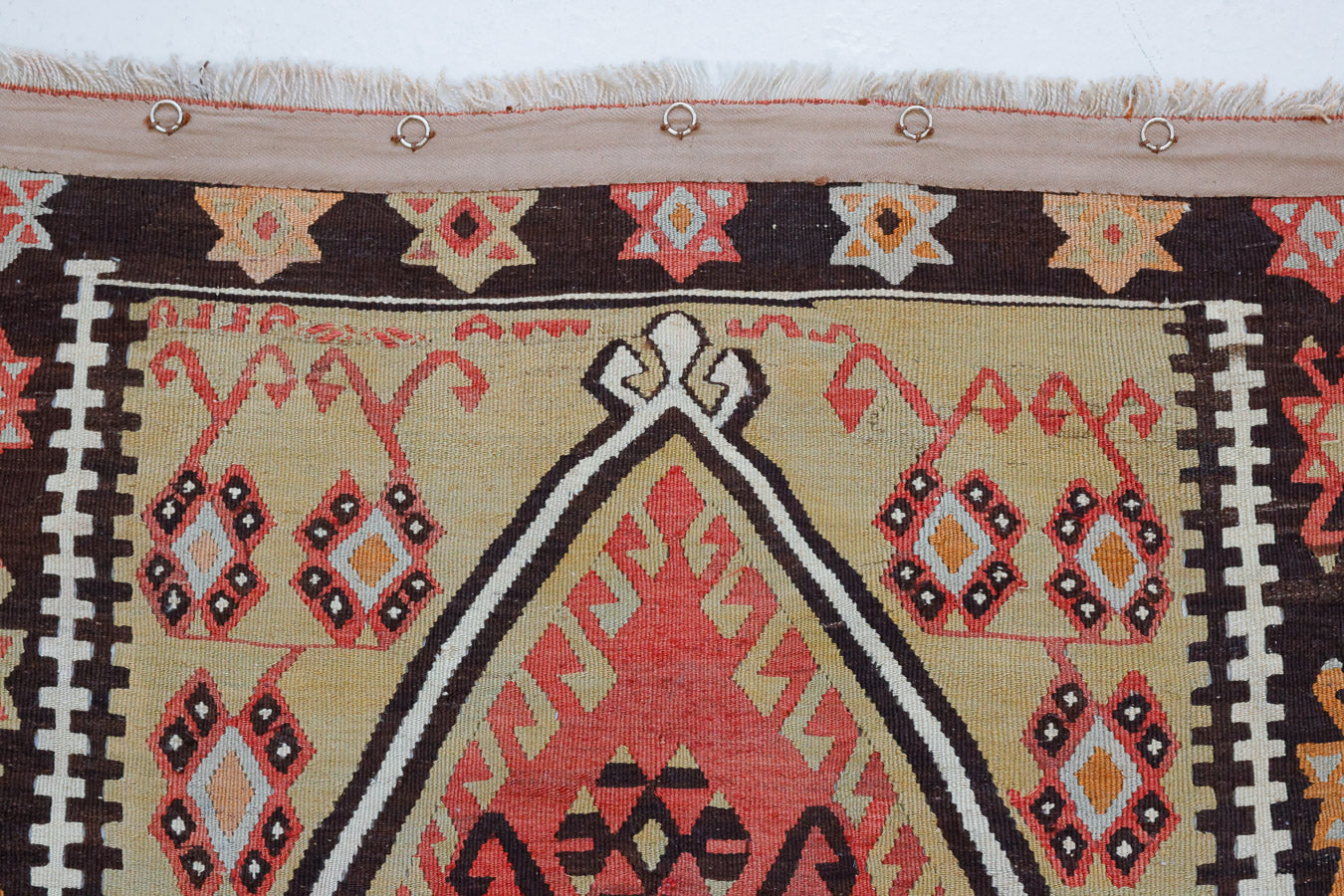 Delphi is a bold, geometric Anatolian kilim. Hand-woven on village and nomadic looms in vivid, naturally dyed colours, a tradition stretching back thousands of years. Kilims were woven for the practicalities of daily life and used as floor and wall coverings, storage bags, and prayer mats. Delphi features a rosey pink field scattered with a geometric motif. A black border is decorated with the Anatolian star motif traditionally associated with happiness.
