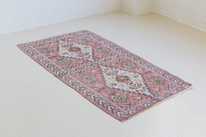 Melissa is an Anatolian Hakkari kilim rug with a Senneh design. Hand-woven on village and nomadic looms in vivid, naturally dyed colours. Kilims were woven for the practicalities of daily life and used as floor and wall coverings, storage bags, and prayer mats. Melissa features a soft pink field scattered with the classic Anatolian fertility motif, set within a soft purple border depicting the eye motif, traditionally used to protect from harm.