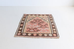 Delphi is a bold, geometric Anatolian kilim. Hand-woven on village and nomadic looms in vivid, naturally dyed colours, a tradition stretching back thousands of years. Kilims were woven for the practicalities of daily life and used as floor and wall coverings, storage bags, and prayer mats. Delphi features a rosey pink field scattered with a geometric motif. A black border is decorated with the Anatolian star motif traditionally associated with happiness.