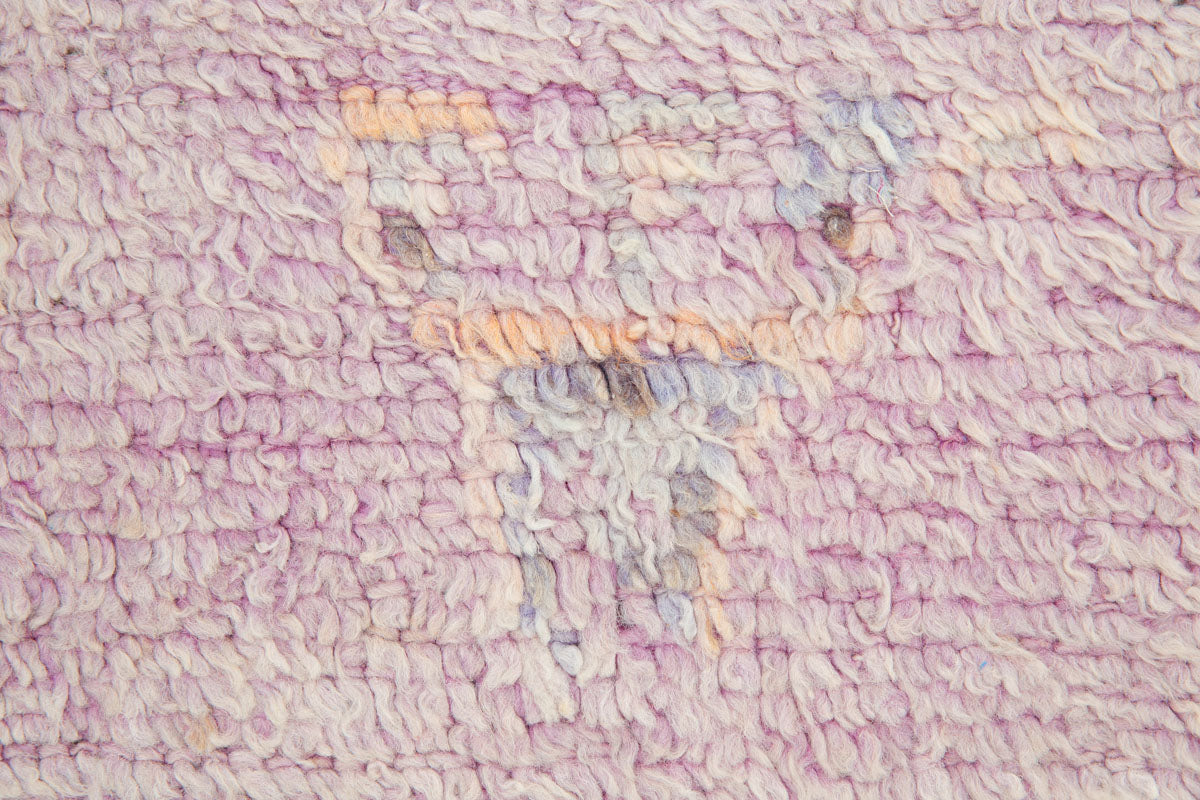 A vintage Boujad rug with a floral and geometric pattern, primarily in shades of pink and orange, showcasing natural dyes.