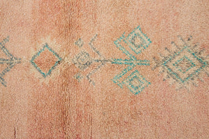 A vintage Boujad rug with a peach and sage green color palette, featuring geometric patterns and berber symbology, approximately 40 years old