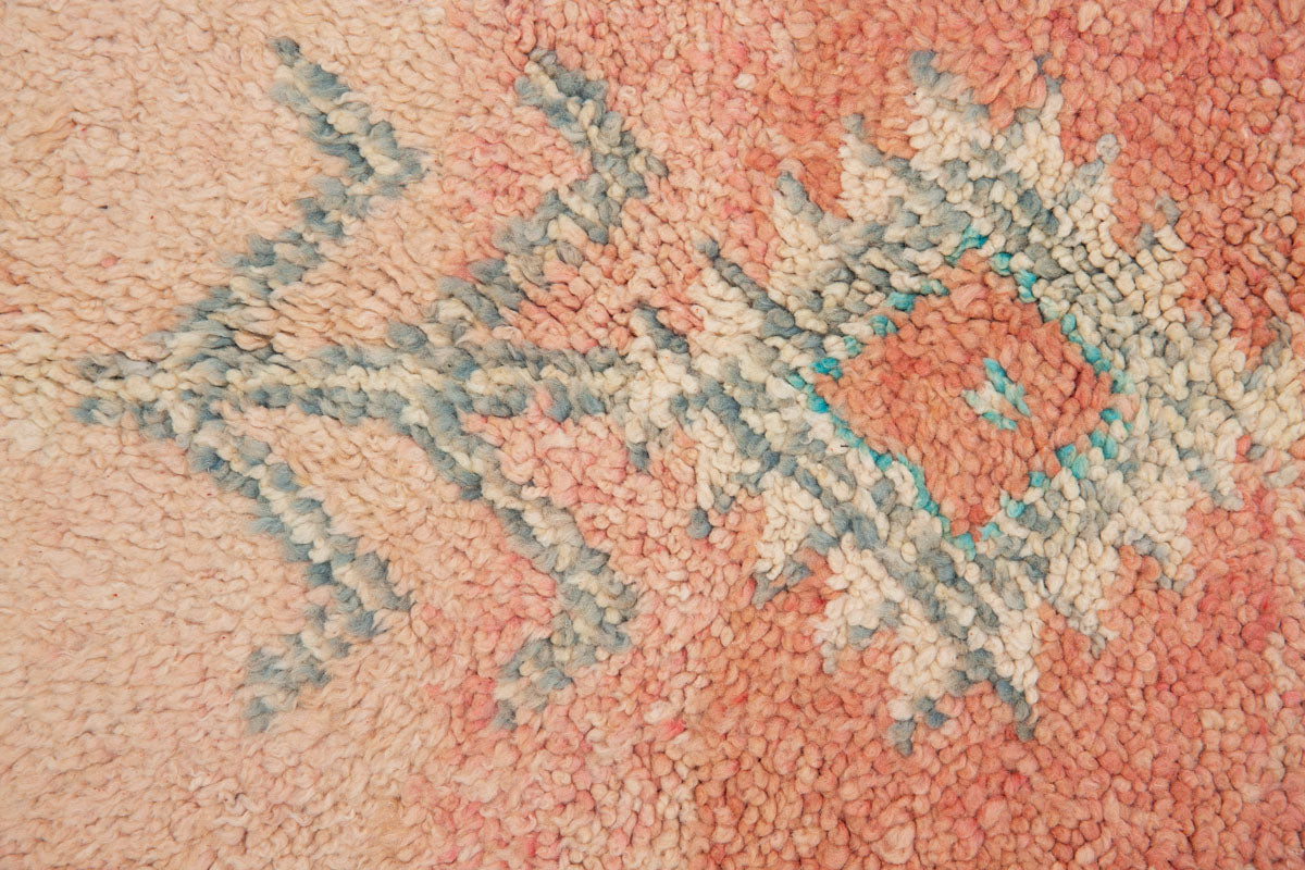 A vintage Boujad rug with a peach and sage green color palette, featuring geometric patterns and berber symbology, approximately 40 years old