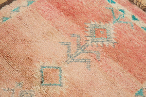 A vintage Boujad rug with a peach and sage green color palette, featuring geometric patterns and berber symbology, approximately 40 years old