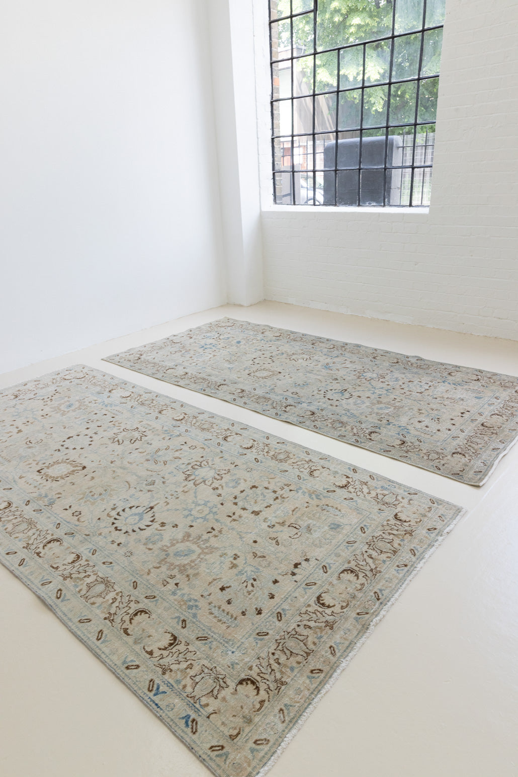 This pair of vintage handknotted Persian rugs are from the Tabriz region. Perisa is one of the oldest rug weaving centres in the world featuring floral patterns and muted colours as seen on these carpets.