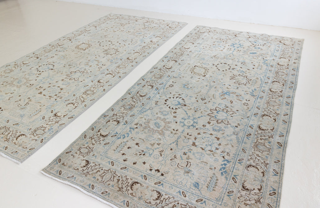 This pair of vintage handknotted Persian rugs are from the Tabriz region. Perisa is one of the oldest rug weaving centres in the world featuring floral patterns and muted colours as seen on these carpets.