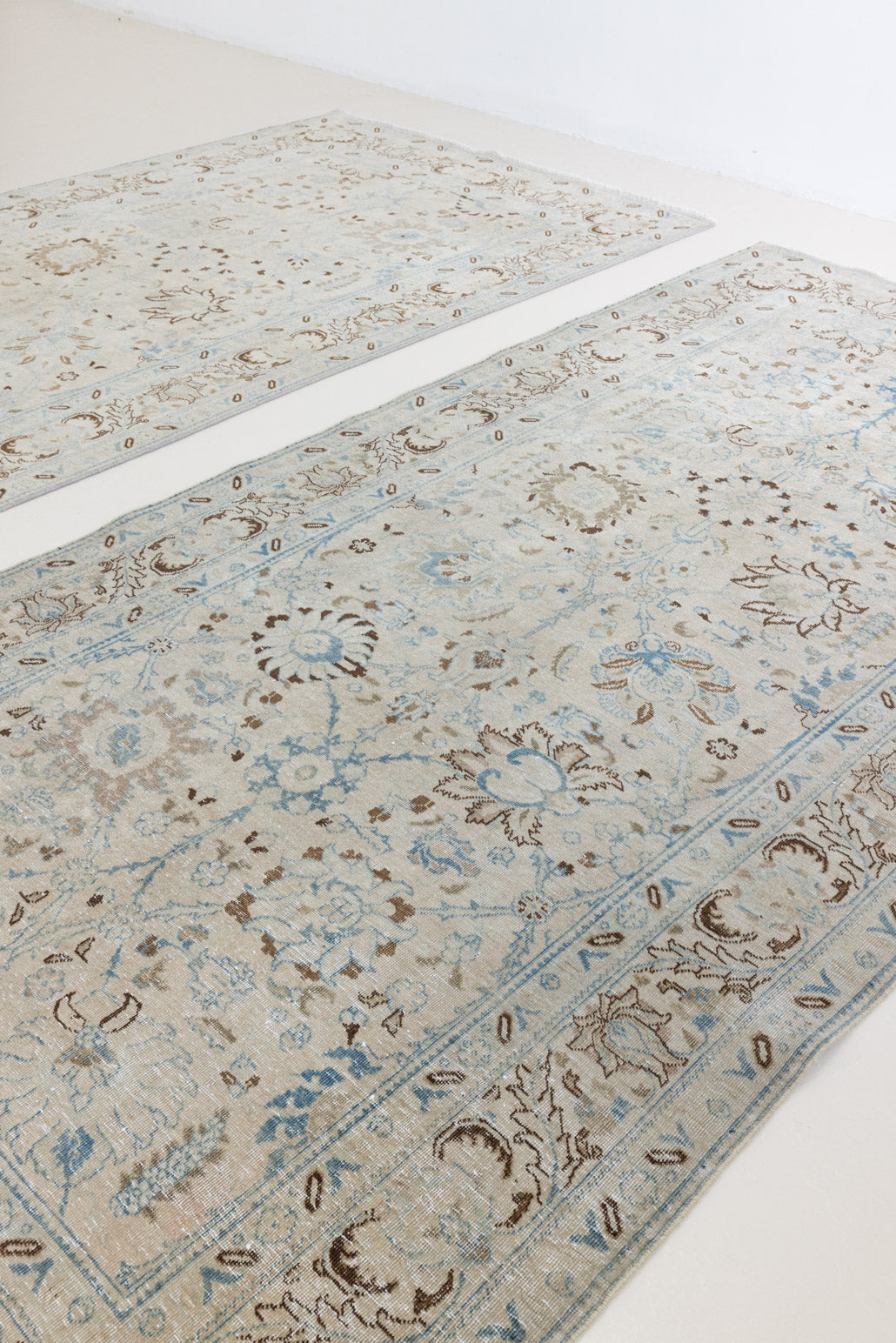 This pair of vintage handknotted Persian rugs are from the Tabriz region. Perisa is one of the oldest rug weaving centres in the world featuring floral patterns and muted colours as seen on these carpets.