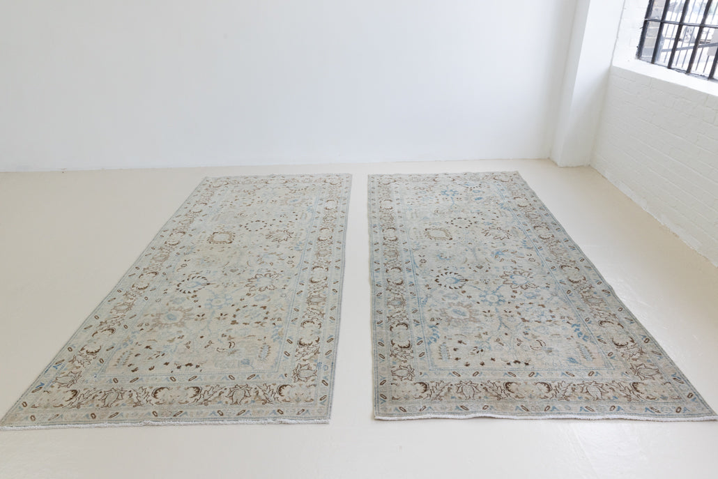 This pair of vintage handknotted Persian rugs are from the Tabriz region. Perisa is one of the oldest rug weaving centres in the world featuring floral patterns and muted colours as seen on these carpets.