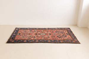 Lilian rugs were handwoven in a small village in Western Iran and often feature floral and geometric patterns as seen here. This small vintage carpet features a soft pink and blue colour palette and an intricate design inspired by nature.