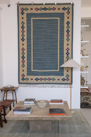 Lumi is a signed vintage Swedish flatweave rug by Anna-Greta Sjöqvist, featuring a calm blue field framed by ivory borders and delicate geometric motifs. Handwoven in wool using the traditional rölakan technique.