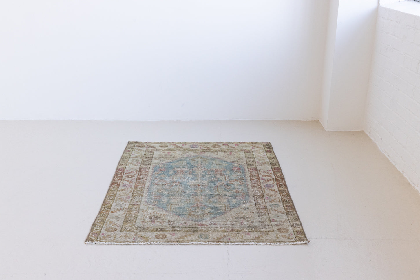 Olive is a Mahal Persian carpet featuring a large central medallion in soft blue and a wide floral boarder with vine scrollwork.