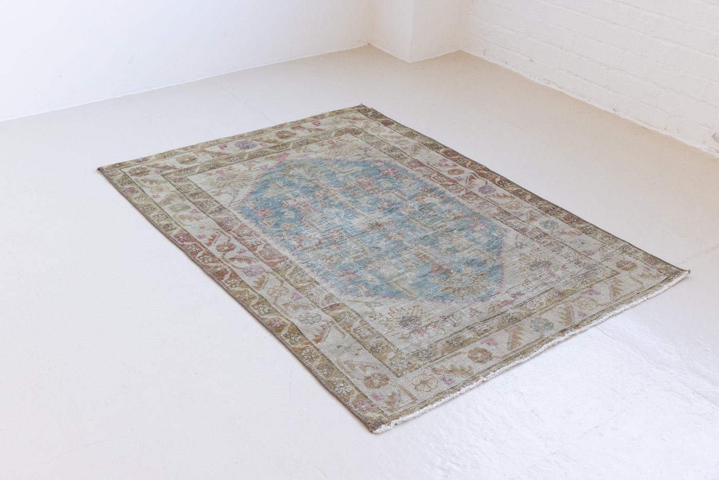 Olive is a Mahal Persian carpet featuring a large central medallion in soft blue and a wide floral boarder with vine scrollwork.