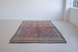 Beni M’guild thick piled carpet. Rug features a dark blue geometric pattern on a peachy pink background.