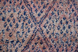 Beni M’guild thick piled carpet. Rug features a dark blue geometric pattern on a peachy pink background.