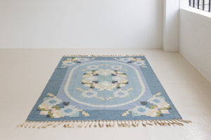 Ingo is a vintage rug handwoven in Sweden by textile designer Ingegerd Silow. Featuring a floral geometric pattern in blues. greens. pinks and black.